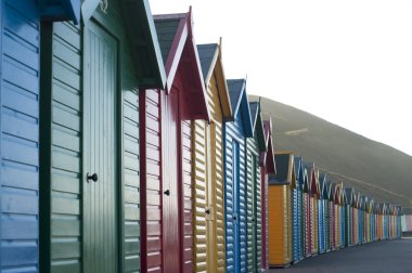 Row of colorful wooden beach huts clipart