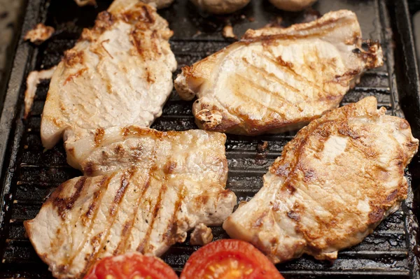 Grilled pork chops and tomatoes on a griddle — Stock Photo, Image