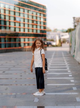 a girl in a school uniform with a backpack walks around the city