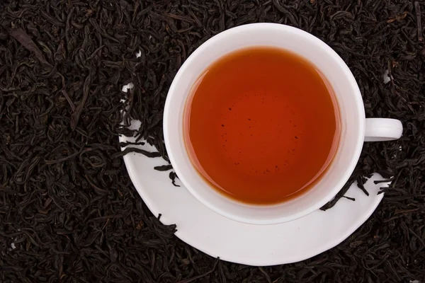 Csésze tea, tea levelek mint háttér. Stock Kép