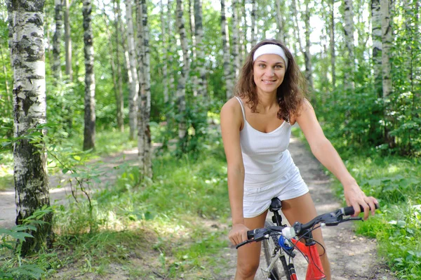 Actieve brunette vrouw op rode fiets — Stockfoto