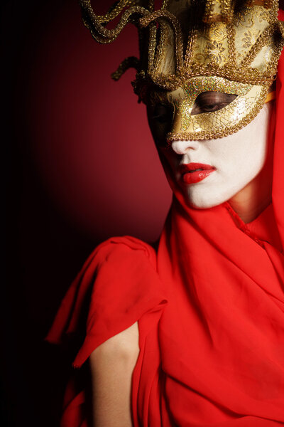 Closeup portrait of sexy woman in golden theater mask for desire concept