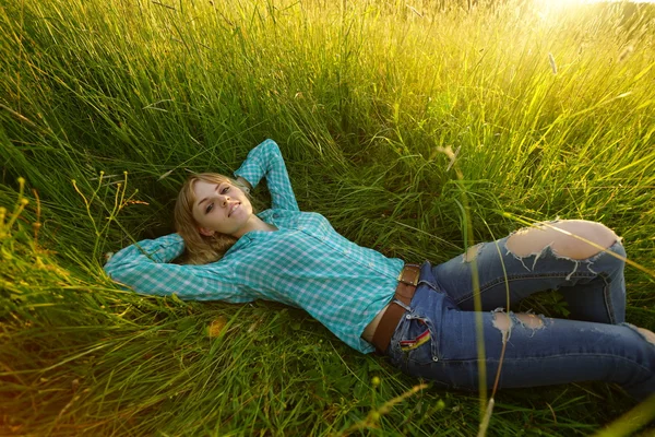 Jonge vrouw liggen in het hoge gras — Stockfoto