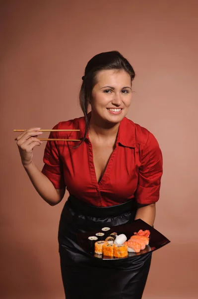 Mujer vestida de rojo con palillos y plato de sushi — Foto de Stock