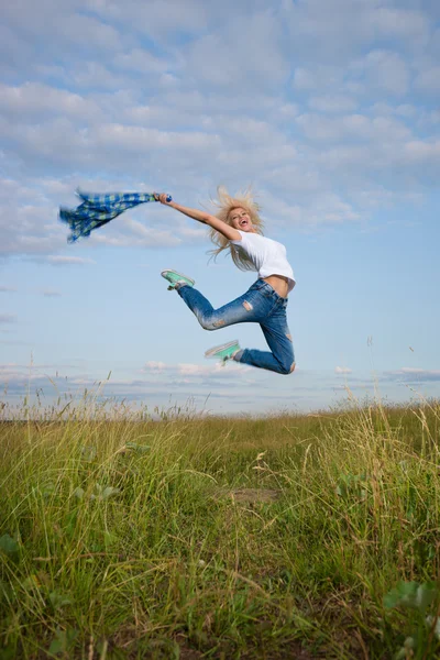 Женщина прыгает в зеленое травяное поле — стоковое фото