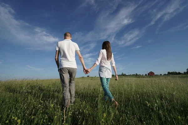 Pareja caminando a través de campo verde — Foto de Stock