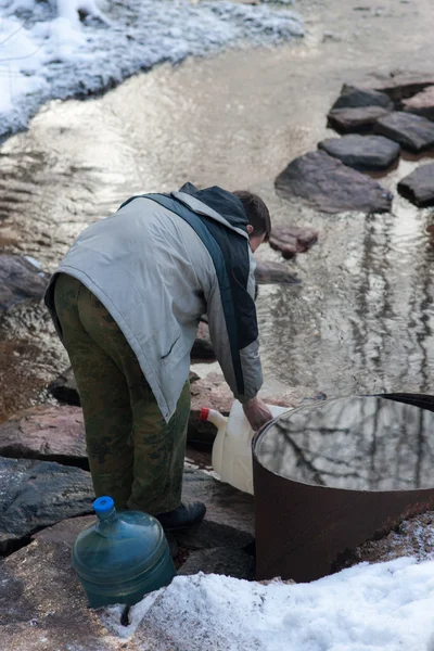 Hombre recoge agua en un recipiente —  Fotos de Stock