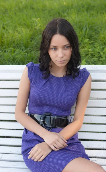 Menina sentada em um banco branco — Fotografia de Stock