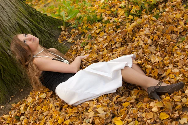 Ragazza su foglie di autunno — Foto Stock