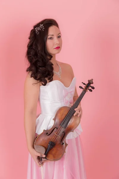 粉红背景上一个拉小提琴的女孩的肖像 — 图库照片