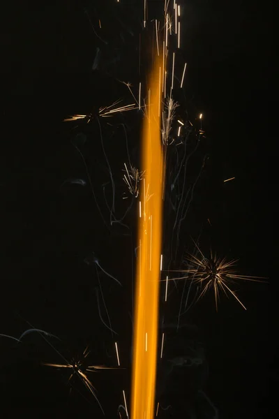 黒の背景に火花とオレンジ色の炎 — ストック写真