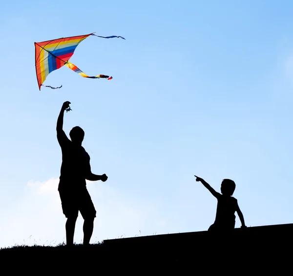 De lancering van een vlieger in de lucht. silhouetten man en kinderen. — Stockfoto
