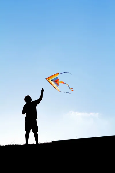 Einen Drachen in den Himmel steigen zu lassen. Silhouette eines Mannes. — Stockfoto