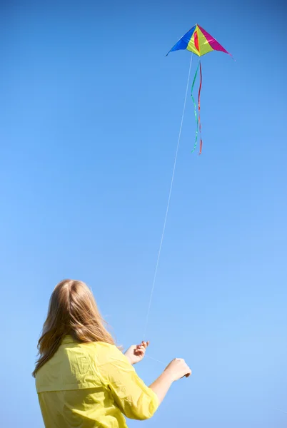 Drachen auf einem Seil gegen den Himmel. Mädchen hält Seil. — Stockfoto