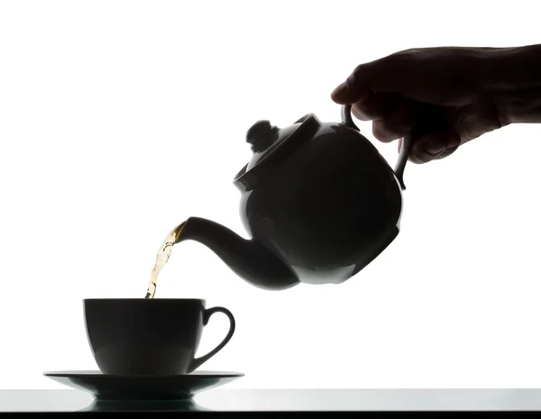 Bule derramando chá em uma xícara. Silhueta — Fotografia de Stock