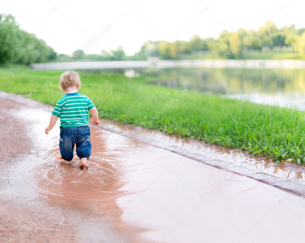 Child walks on the puddles after the rain