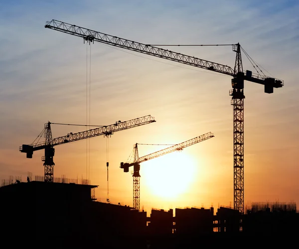 Siluetas de grúas de construcción contra el cielo nocturno —  Fotos de Stock