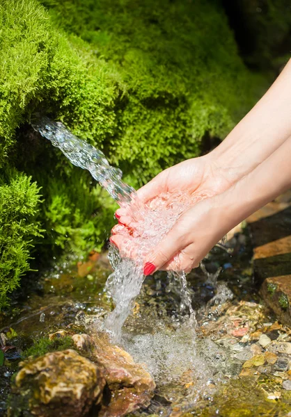 Spring water flows in female hands — Stock Photo, Image