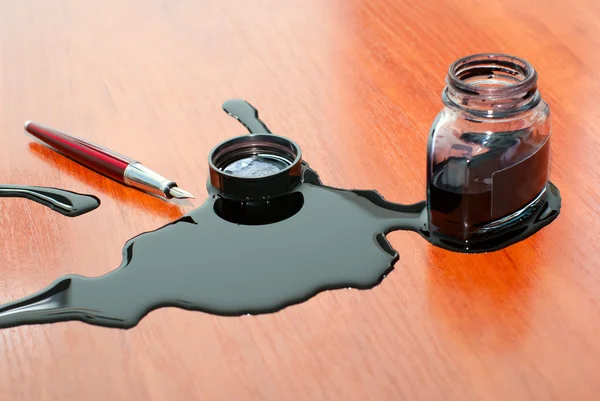 Zwarte inkt morserij in de buurt van rode pen op tafel — Stockfoto