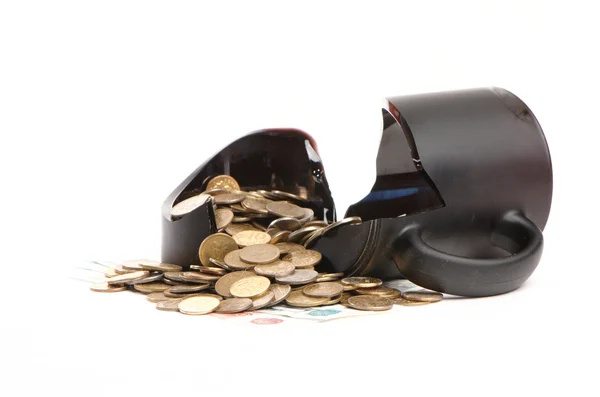 Taza rota y monedas sobre una mesa, fondo blanco — Foto de Stock