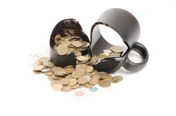 Broken mug and coins on a table, white background — Stock Photo, Image