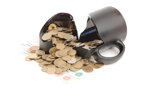 Taza rota y monedas sobre una mesa, fondo blanco — Foto de Stock