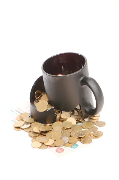 Taza rota y monedas sobre una mesa, fondo blanco — Foto de Stock