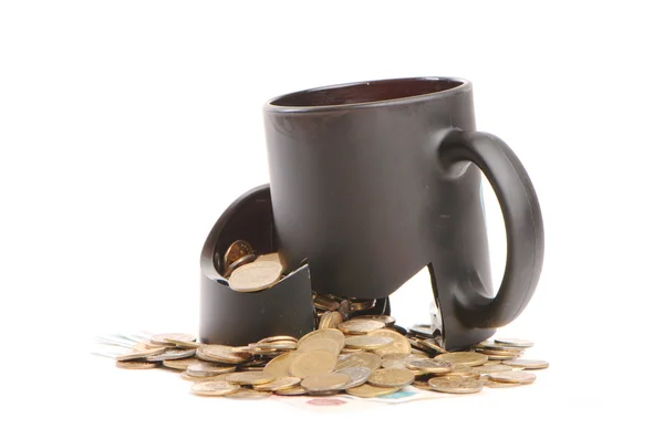 Taza rota y monedas sobre una mesa, fondo blanco — Foto de Stock