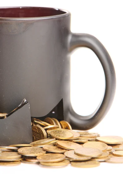 Taza rota y monedas sobre una mesa, fondo blanco — Foto de Stock