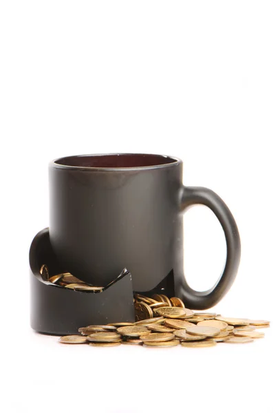 Broken mug and coins on a table, white background — Stock Photo, Image