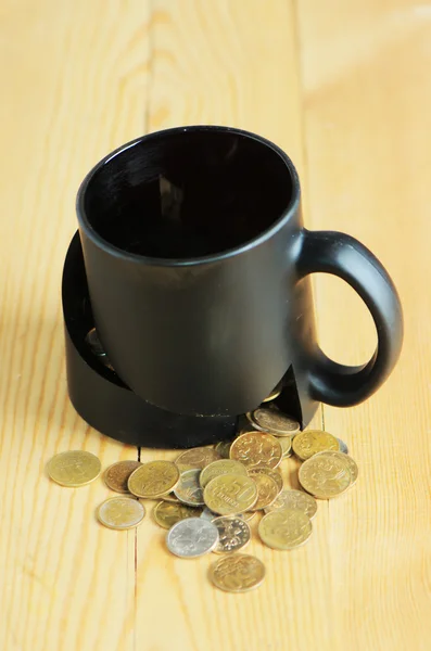 Broken mug and coins on a table — Stock Photo, Image