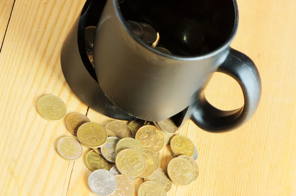 Broken mug and coins on a table — Stock Photo, Image
