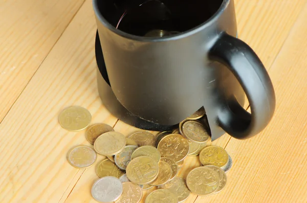 Broken mug and coins on a table — Stock Photo, Image