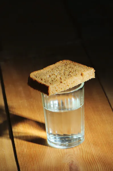 Verre de vodka et une tranche de pain sur une table en bois — Photo