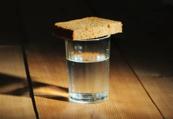 Verre de vodka et une tranche de pain sur une table en bois — Photo
