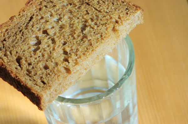 Glass of vodka and a slice of bread on a wooden table — Stock Photo, Image