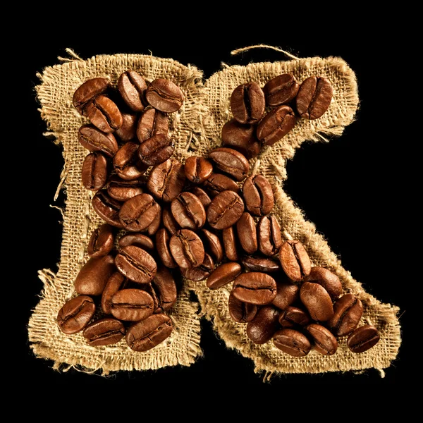 Alphabet from coffee beans on fabric texture isolated on black — Stock Photo, Image