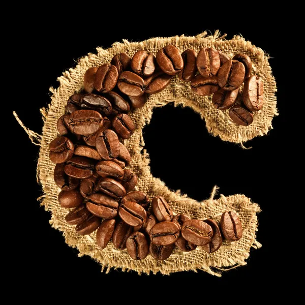 Alphabet from coffee beans on fabric texture isolated on black — Stock Photo, Image