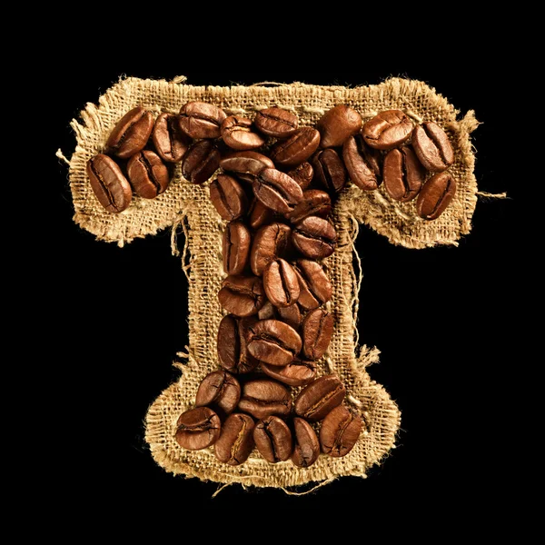 Alfabet z ziaren kawy na tekstura tkanina na czarnym tle — Zdjęcie stockowe