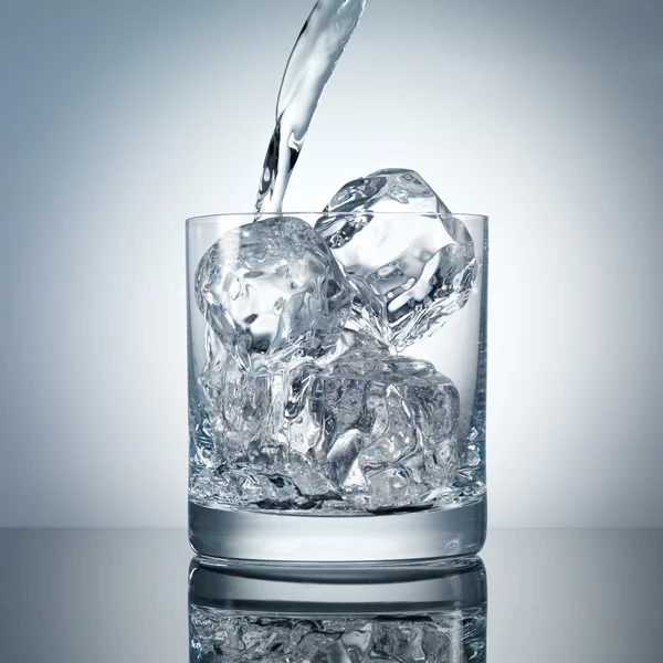 Gieten van water in een glas met perfecte ijs — Stockfoto