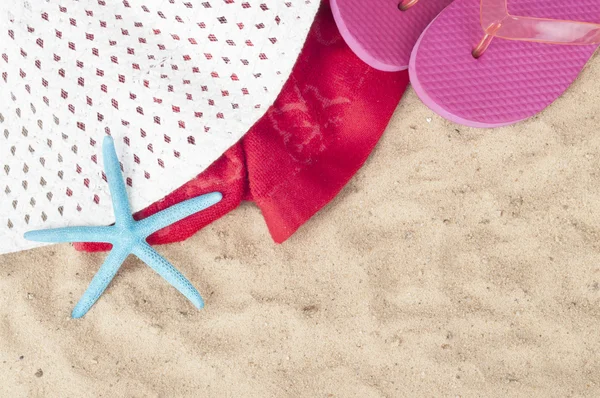 Beach items with towel,flip flops and starfish on a sand background — Stock Photo, Image