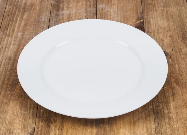 Empty white plate on wooden table — Stock Photo, Image
