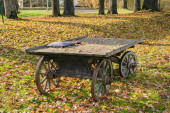 Starý dřevěný vozík stojí v parku, podzim
