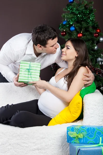 Happy pregnant couple near the christmas tree — Stock Photo, Image