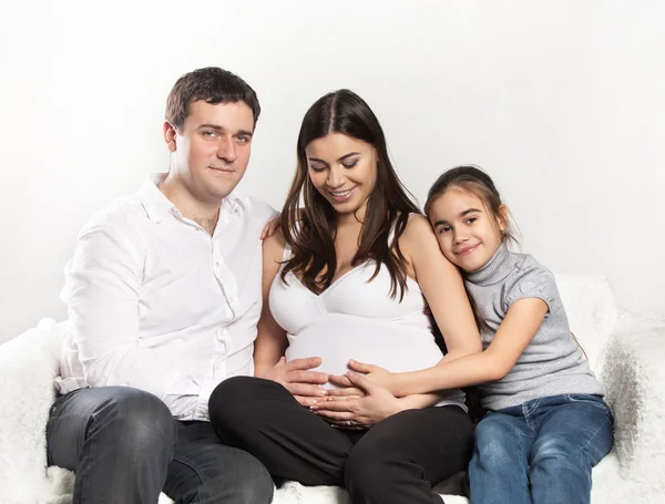 Junge schwangere Familie auf dem Sofa — Stockfoto