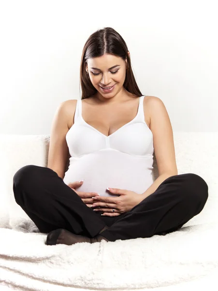 Kobieta w ciąży brunetka na kanapie — Zdjęcie stockowe