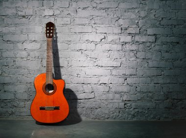 Acoustic guitar leaning on grungy wall clipart
