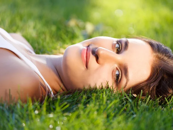 年轻美丽的女孩在绿色草地上放松 免版税图库照片