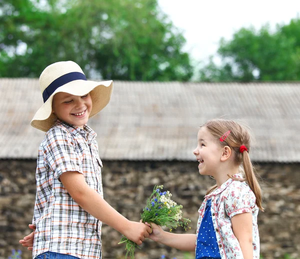 小さな男の子は、小さな女の子に花を与える — ストック写真