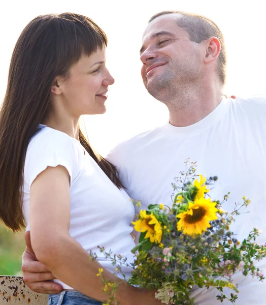 Happy young smiling couple with flowers — Stock Photo, Image